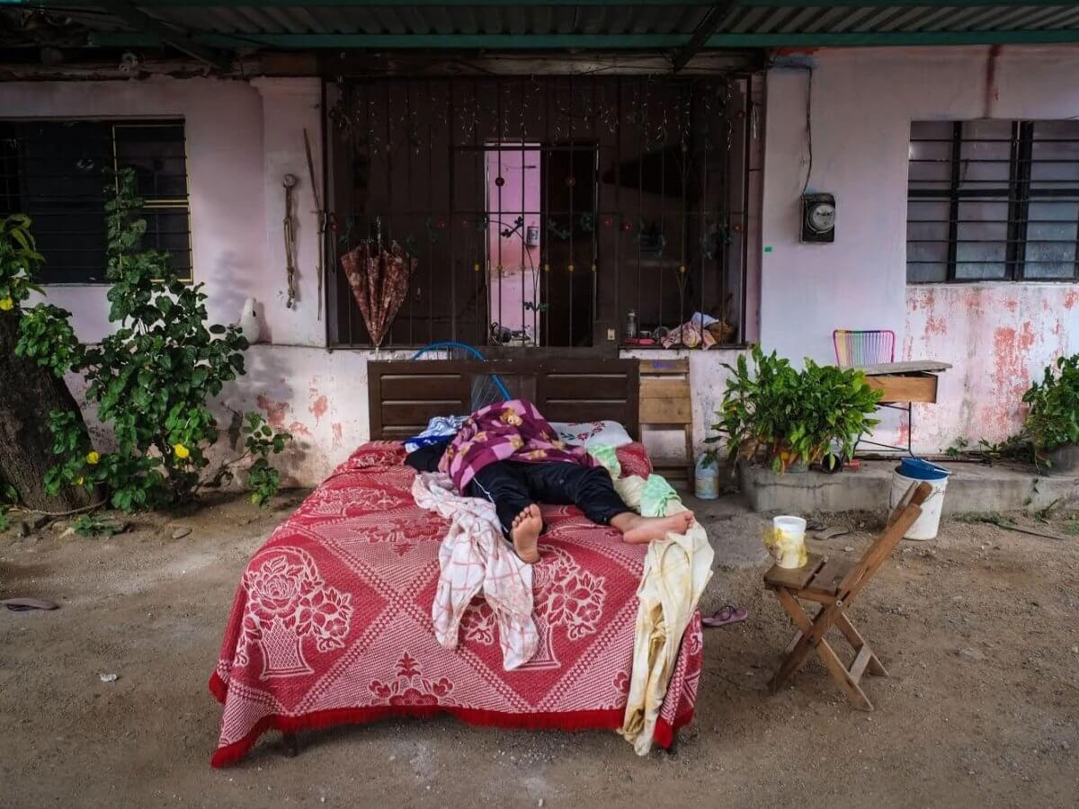 Un hombre duerme en una cama afuera de su casa