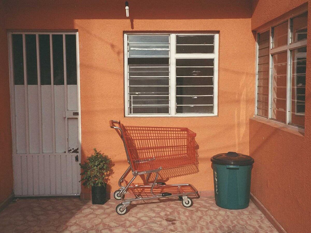 Un carrito de super naranja sobre dentro de un patio de una casa naranja