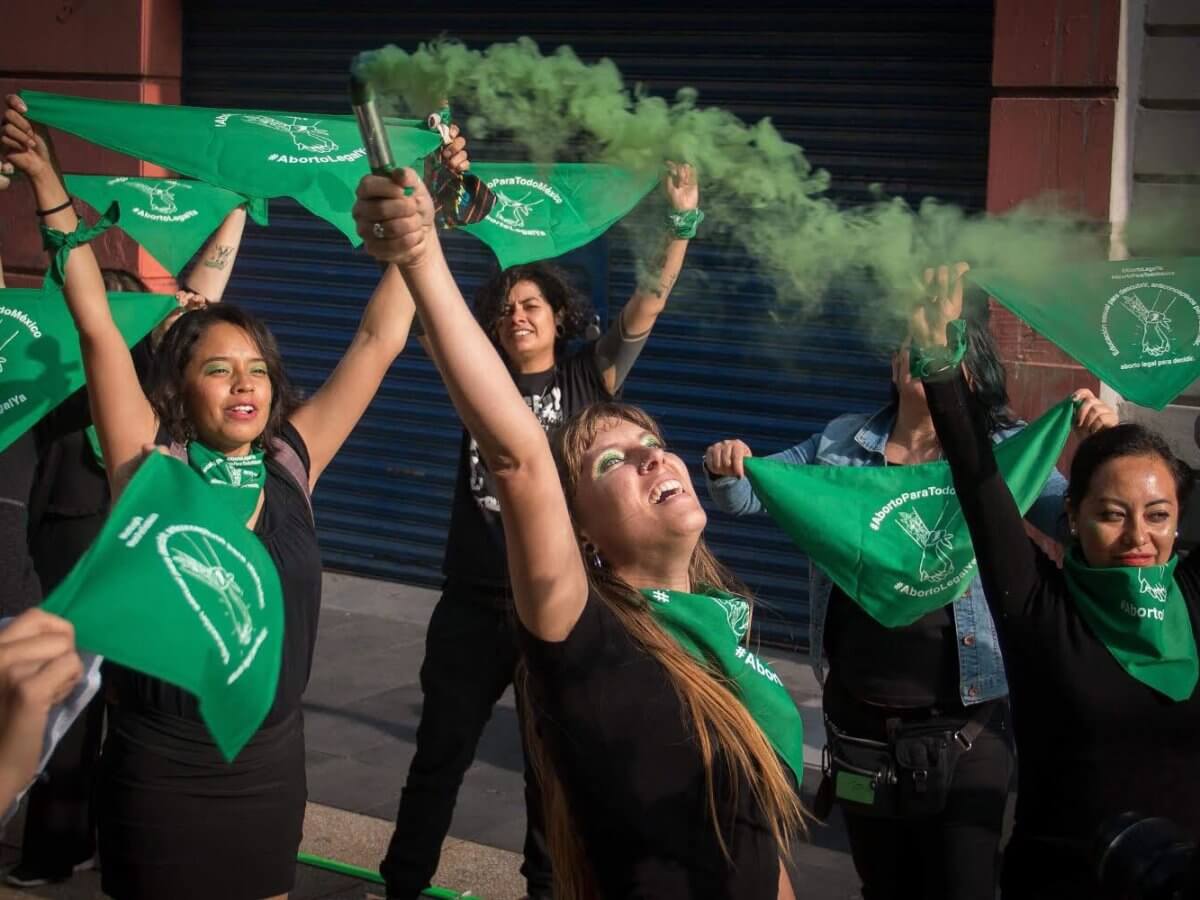 Mujeres marchan con pañoletas verdes y gas